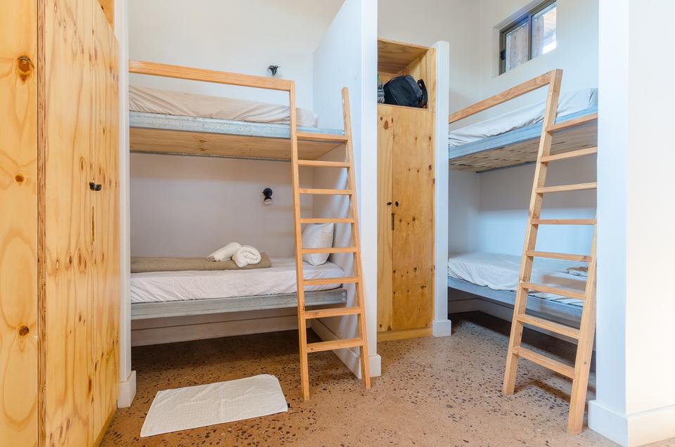 Bunks with ladders and a wooden cupboard in a dorm.